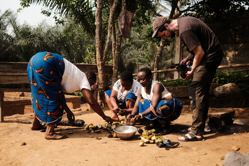 Cameraman filming local women preparing bush mango seeds together in a village setting