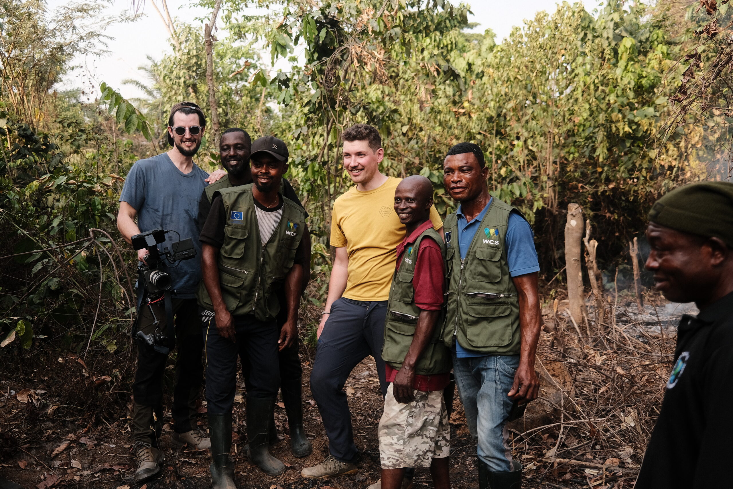 Film crew and WCS conservation rangers posing together in a forest clearing