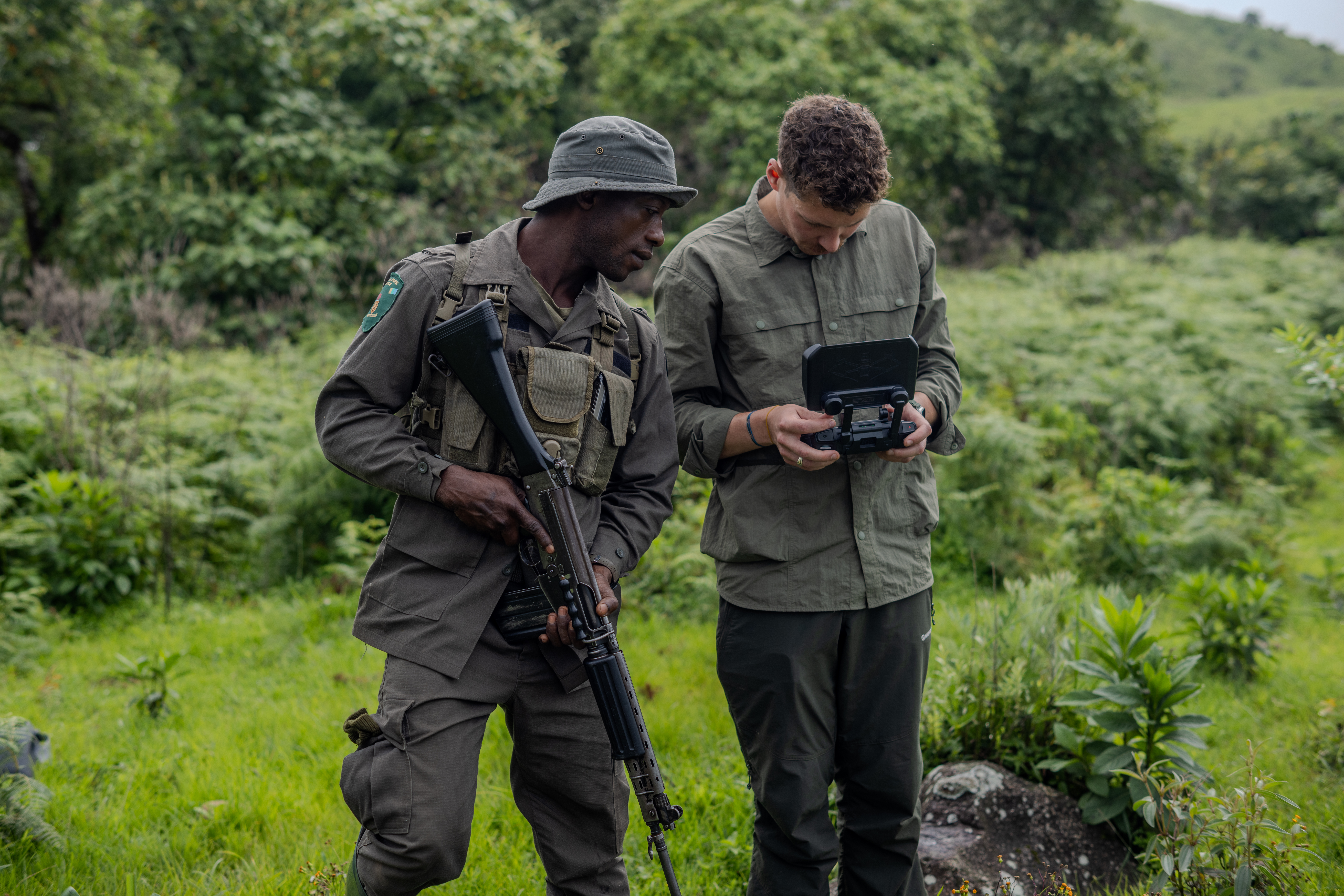 Park ranger and filmmaker reviewing a drone monitor together in the forest at Gashaka Gumti