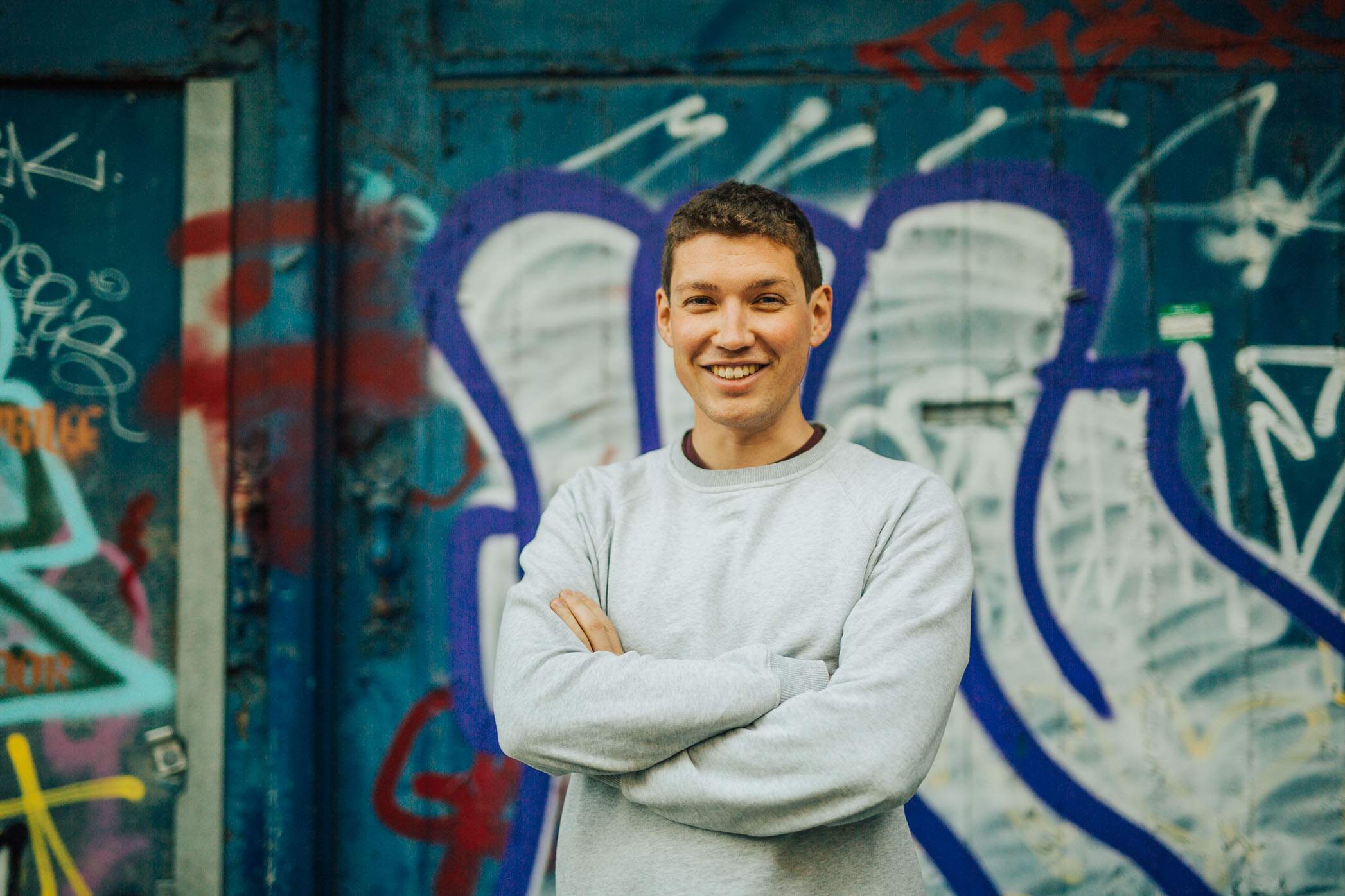 Tom Richards, founder of Forest Spirit Media, smiling in front of a graffiti-covered wall