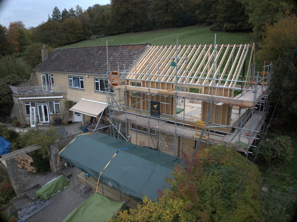 Aerial drone view of a house mid-renovation, with scaffolding and an exposed timber roof extension